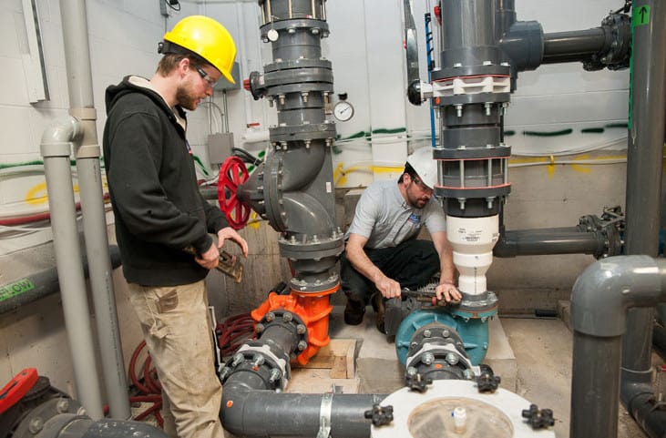 Commercial plumbers working on building piping